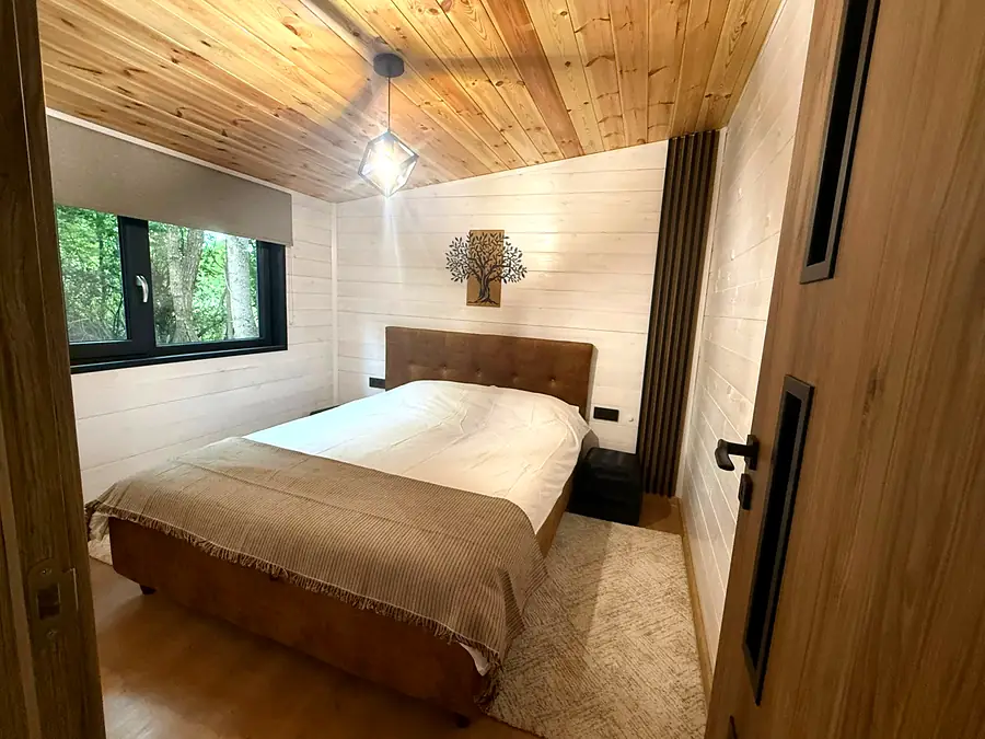 Dormitor cu pat matrimonial și vedere la pădure, cabana Wild Crib