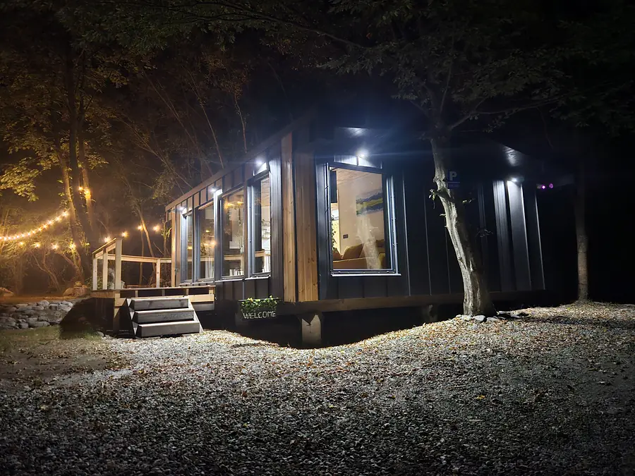Cabana Wild Crib luminată noaptea, în pădurea din Valea Avrigului